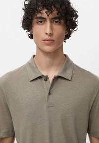 Polo tričko v olivově zelené barvě, krátké rukávy, zapínání na dva knoflíky, měkká textura, standardní límec, s minimálním detailem prošívání.