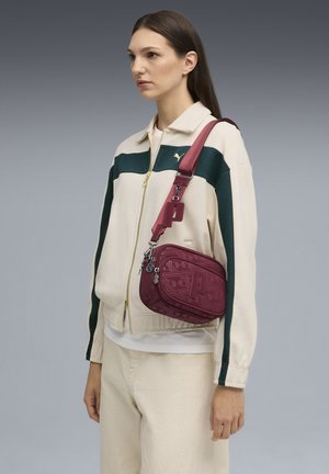 Sac bandoulière bordeaux en matériau texturé, présentant un motif géométrique, une sangle réglable et des accents en métal.