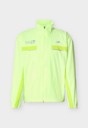 Μπουφάν νέον κίτρινο υψηλής ορατότητας με πλήρες εμπρόσθιο φερμουάρ, ανακλαστικές λωρίδες, ελαστικά μανίκια και λογότυπα στο στήθος, σχεδιασμένο για ασφάλεια σε εξωτερικούς χώρους.