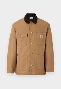 Brun lærred jakke med en mørkebrun fløjlskrave, gyldne trykknapper og flere frontlommer med et logo patch.