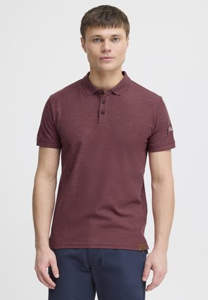 Polo burdeos de algodón texturizado, con una tapeta de dos botones, mangas cortas y un detalle de logo en la manga.