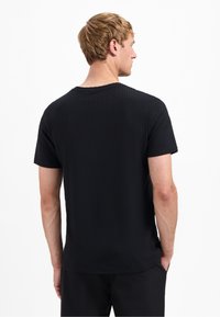 Zwarte t-shirt met korte mouwen, voorzien van een textuur met wafelpatroon en een ronde hals. Heeft een relaxte pasvorm en details aan de zijnaad.