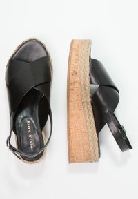 Černé kožené sandály na klínku s juty jako espadrille-styl střídavým středem, s kříženými popruhy a nastavitelným nártním popruhem.