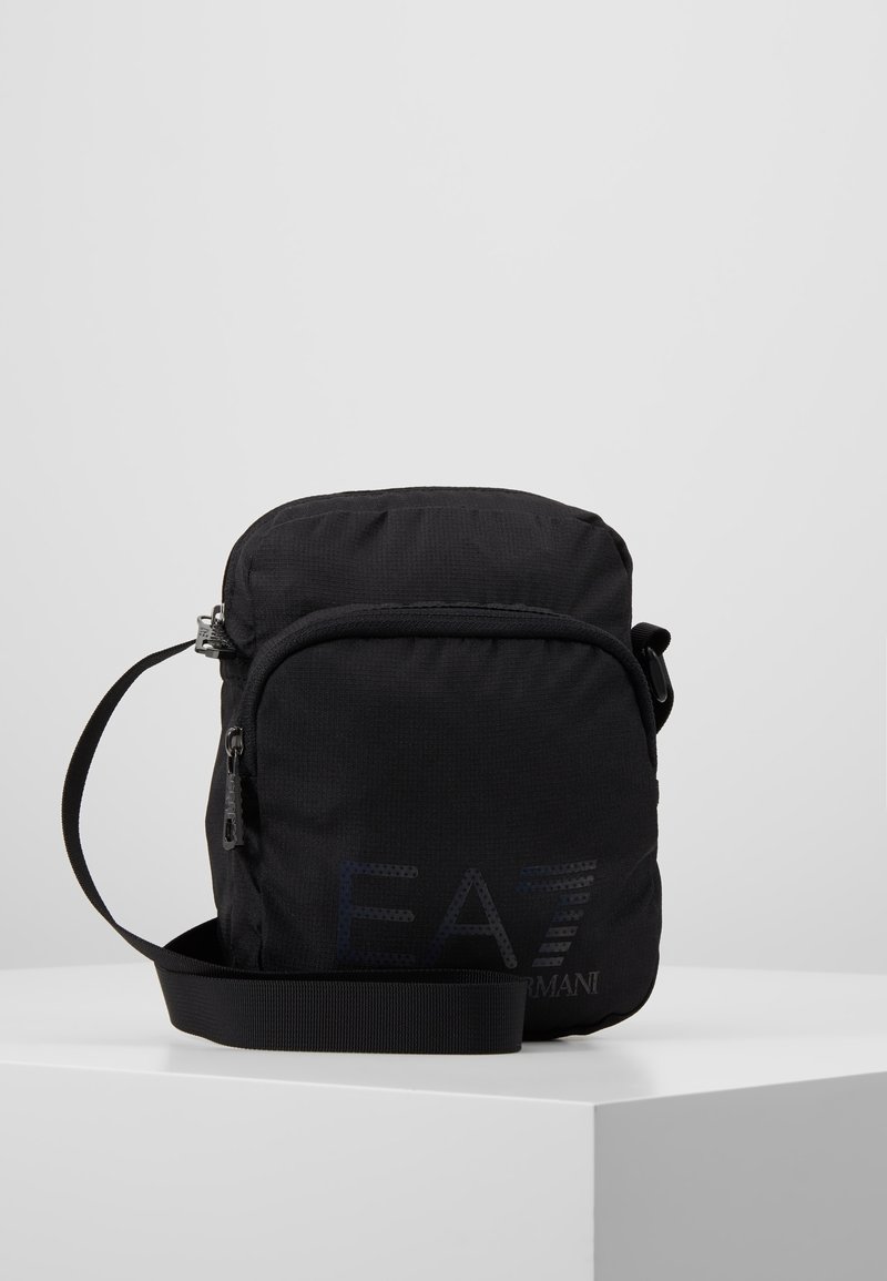 Borsa a tracolla nera in nylon con chiusura a zip, tracolla regolabile e logo EA7 inciso sul davanti. Design compatto con texture liscia.