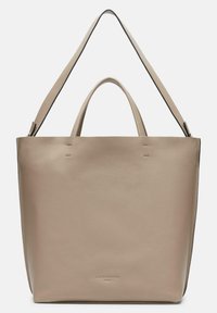 Beżowa skórzana torba tote z podwójnymi uchwytami i paskiem na ramię. Gładka tekstura z delikatnym przeszyciem i logo marki wytłoczonym z przodu.