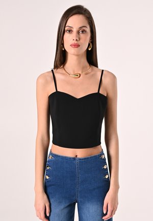 Top nero corto con spalline sottili e scollatura a cuore, abbinato a jeans blu a vita alta con dettagli in bottone dorato.