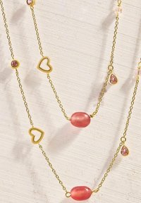 Collar dorado con gemas rosas, acentos en forma de corazón y cuentas ovaladas. Diseño de cadena delicada con formas y tamaños variados.