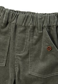 Pantalons en velours côtelé de couleur vert olive avec une taille élastique, dotés de deux poches avant et d'un détail de bouton marron. Tissu texturé à côtes.