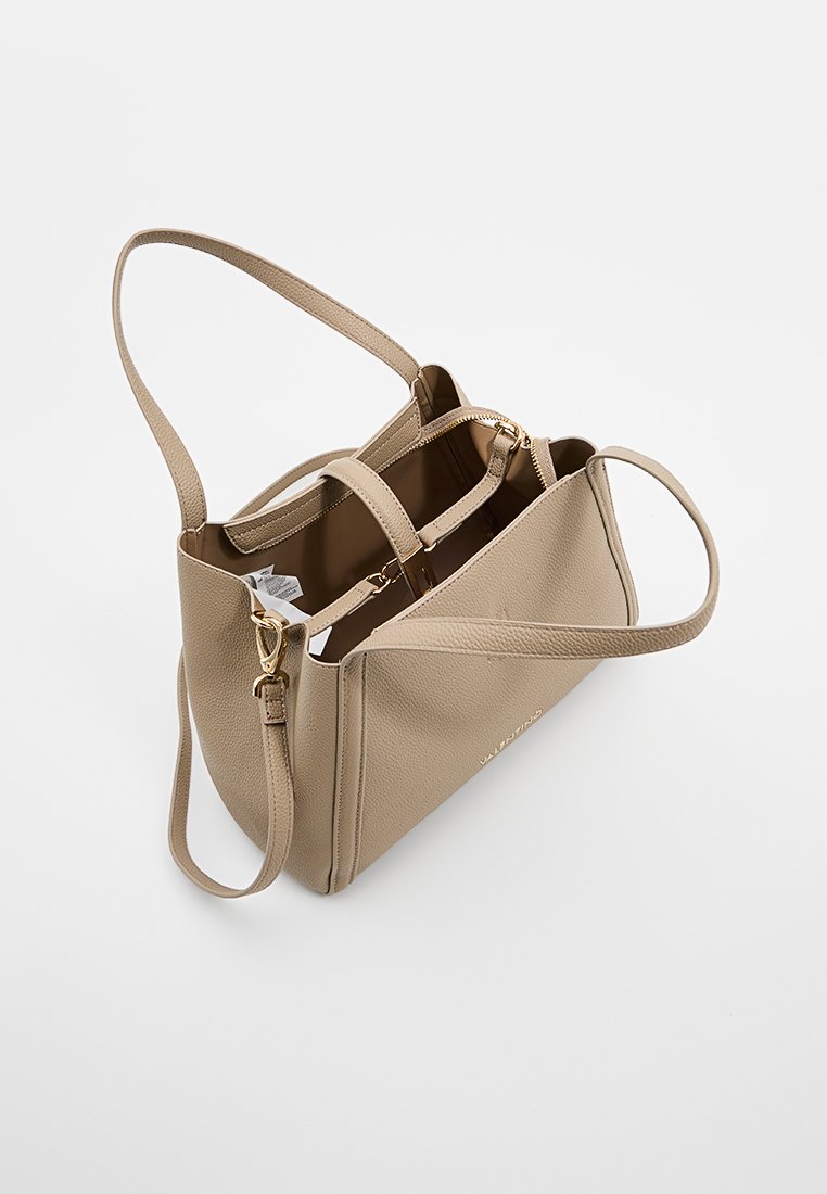 Leren handtas in tan kleur met een gestructureerd ontwerp, voorzien van twee compartimenten, handvatten aan de bovenkant en een verstelbare schouderband. Accenten van goudkleurig beslag.