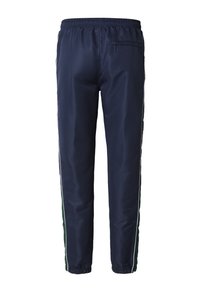 Granatowe spodnie sportowe wykonane z gładkiego, lekkiego materiału. Posiadają białe paski po bokach i elastyczne mankiety. Wyposażone w tylną kieszeń na zamek.