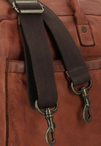 Sac messager en cuir marron avec une finition texturée. Dispose d'une bandoulière en cuir marron foncé durable et de quincaillerie en métal avec des fermoirs à homard.