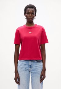 Rød bomulds t-shirt med rund hals og korte ærmer, der har et lille logo på brystet. Bør paired med lyseblå denim jeans.