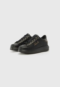 Baskets en cuir noir avec lacets plats, œillets dorés et semelle surélevée. Présente un logo embossé sur le côté et des coutures contrastantes.