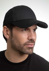 Cappellino da baseball nero realizzato in tessuto testurizzato, con visiera curva e un design semplice. Senza loghi o accenti visibili.