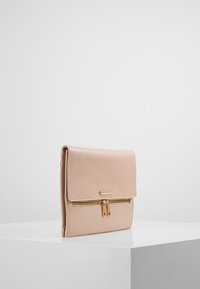 Beige leather handbag with a flap closure, gold hardware, zippered front pocket, and smooth texture. Rectangular shape with minimal design.