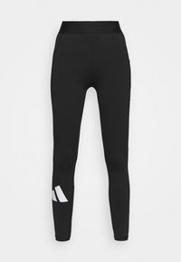 Leggings noirs avec une large ceinture, dotés d'une texture lisse et d'un accent de logo blanc sur la jambe inférieure gauche.