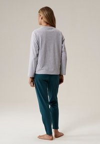 Szara koszula z długim rękawem i okrągłym dekoltem w połączeniu z turkusowymi, dopasowanymi spodniami, oba wykonane z miękkiego materiału, wyświetlane z tyłu.