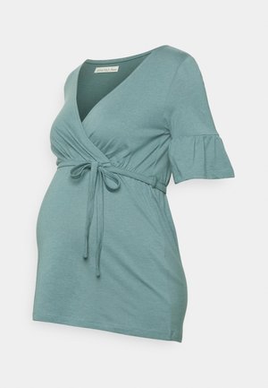 Mentolový těhotenský top s překládaným designem a zavazováním v pase. Krátké, rozšířené rukávy a měkká, lehká látka s hladkou texturou.