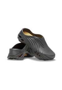 Sabots en plastique gris avec une texture lisse, un design en vagues et des trous ouverts pour la ventilation. Dotés d'une semelle intérieure rembourrée pour le confort.
