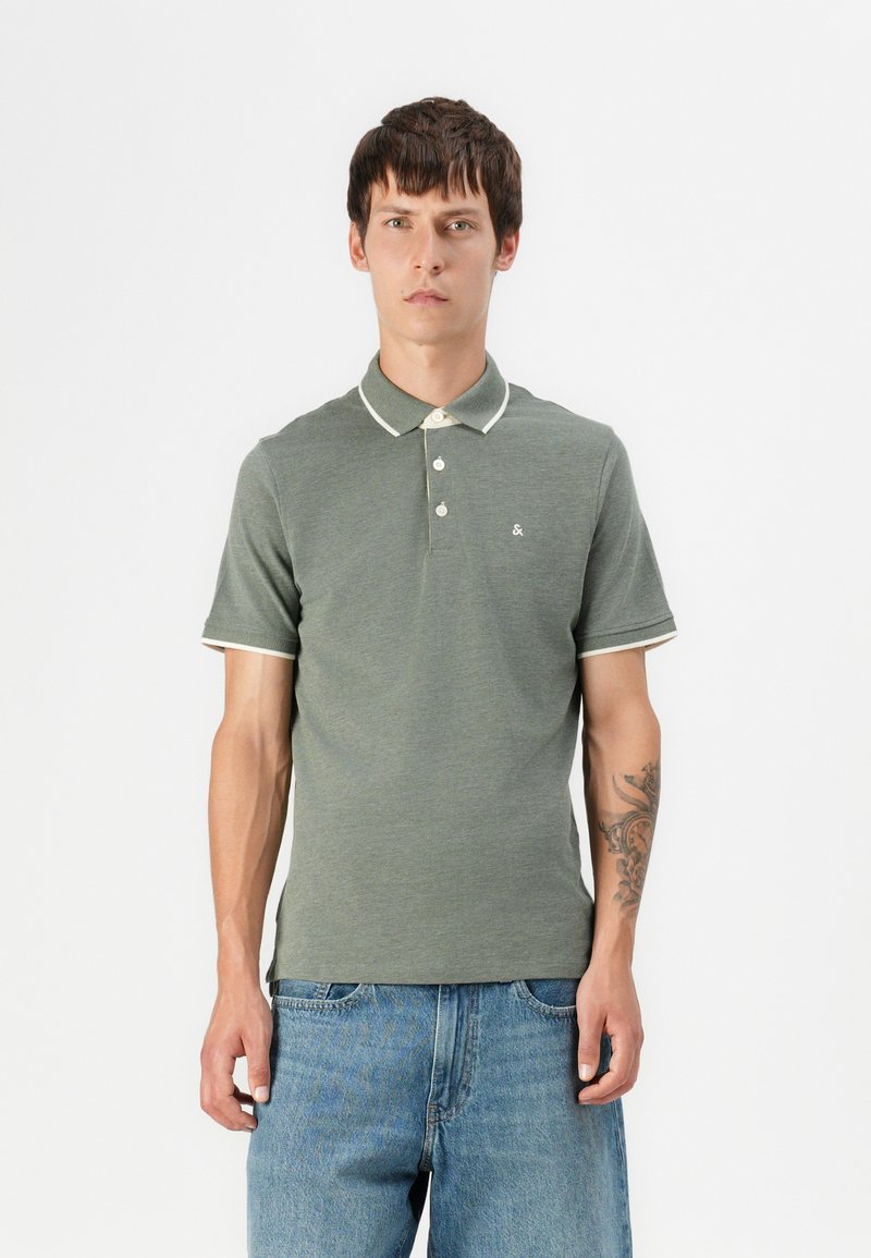 Groene polo met een gestructureerde stof, contrasterende witte kraag en mouwafwerking, een twee-knopen sluiting en een klein logo op de borst.