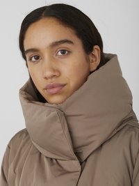 Veste rembourrée marron avec un col haut et surdimensionné. Texture lisse et mate avec un design minimaliste, présentant une silhouette structurée.