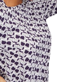 Kurzarmshirt mit einem geometrischen Muster in wechselnden Lila- und Grautönen. Hergestellt aus leichtem, weichem Stoff.