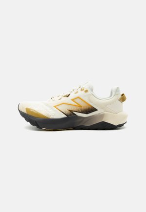 Zapatilla deportiva blanca con logo en degradado amarillo y negro, suela negra y entresuela beige, mostrada de lado sobre un fondo blanco.