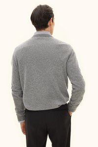 Grauer Strickpullover mit langen Ärmeln, gerippten Bündchen und geradem Saum, getragen über einem Hemd mit einem blau-weißen Streifenmuster.