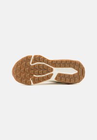Semelle de chaussure avec un motif de gomme. Présente un schéma de couleurs marron et crème et des formes géométriques proéminentes pour l'adhérence.