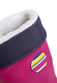 Botte en caoutchouc rose avec un col en tissu bleu marine, une doublure blanche en peluche et un accent rond rayé comportant des tons jaunes et violets.