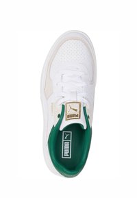 Hvit sneaker med perforert skinnoverdel, beige detaljer, grønn fôr og gull merkevare på tungen og innersålen.