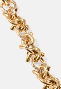 Goldene Kettenarmband mit großen, miteinander verbundenen Gliedern, strukturierten Oberflächen und Strassakzenten für zusätzlichen Glanz und Detail.
