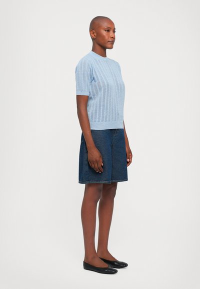 Light blue ribbed knit short-sleeve top, paired with a dark denim skirt, and black flats. Simple, smooth textures; casual design.