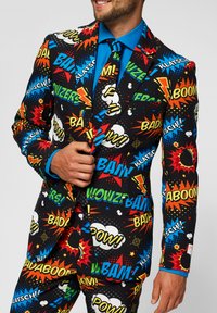 Colorful suit covered in comic-style graphics featuring words like "POW!" and "BAAM!", with a blue shirt and matching tie.