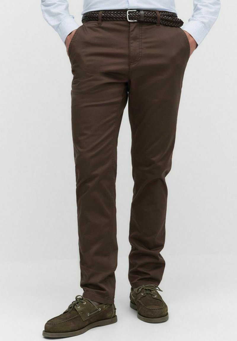 Bruine katoen broek met een rechte pasvorm, voorzien van voorzakken, een gevlochten bruine riem en bijpassende bruine casual schoenen.