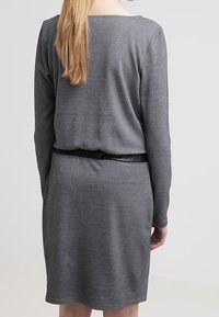 Harmaa neulemekko pitkillä hihoilla, hieman väljä malli ja vyötärölle sidottu vyö. Pehmeä pinta ja yksinkertainen muotoilu venepääntiellä.