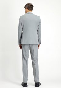 Hellgrauer Anzug mit taillierter Passform, einfachem Schlitz und eleganten Hosen. Aus glattem, leichtem Stoff gefertigt und mit minimalistischen Designdetails.