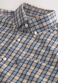 Chemise à carreaux beige, marine et bleu clair avec boutons, col boutonné et petite étiquette de poche avec un motif homard.