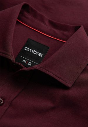 Bordeaux katoenen overhemd met een kraag, voorzien van contrasterende rode stiksels en een zwart label met de tekst "ombre," maat M, stijlkenmerken zichtbaar.