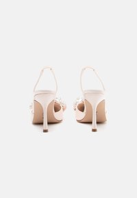 Sandales à talons aiguilles en satin rose avec un talon stiletto effilé et des perles décoratives à l'avant, dotées d'une bride de cheville réglable.