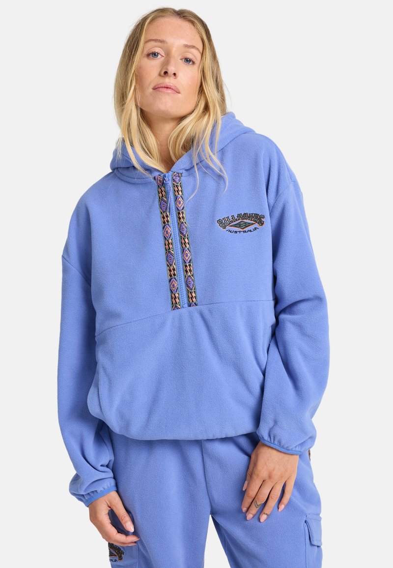 Haut en polaire bleu avec un col à cordon, des détails de motif tribal et un logo à l'avant. Présente une coupe décontractée et des poignets côtelés.