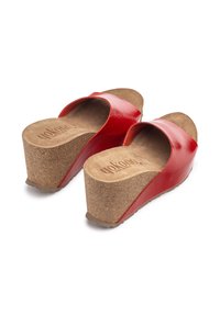 Red wedge sandals with a glossy patent leather upper and cork sole. Features a contoured footbed and open toe design for comfort.