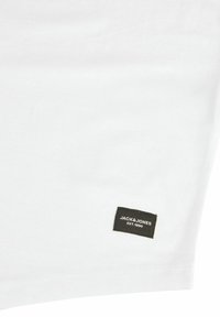 Weißes Baumwoll-T-Shirt, kurzärmlig, mit einem rechteckigen schwarzen Etikett mit weißem Text "JACK & JONES EST. 1990" in der Nähe des Saums.