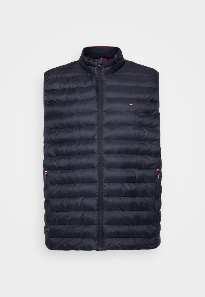 Gilet matelassé bleu marine avec un col remonté, texture matelassée, fermeture éclair sur le devant et poches latérales. Présente un petit logo sur la poitrine gauche.