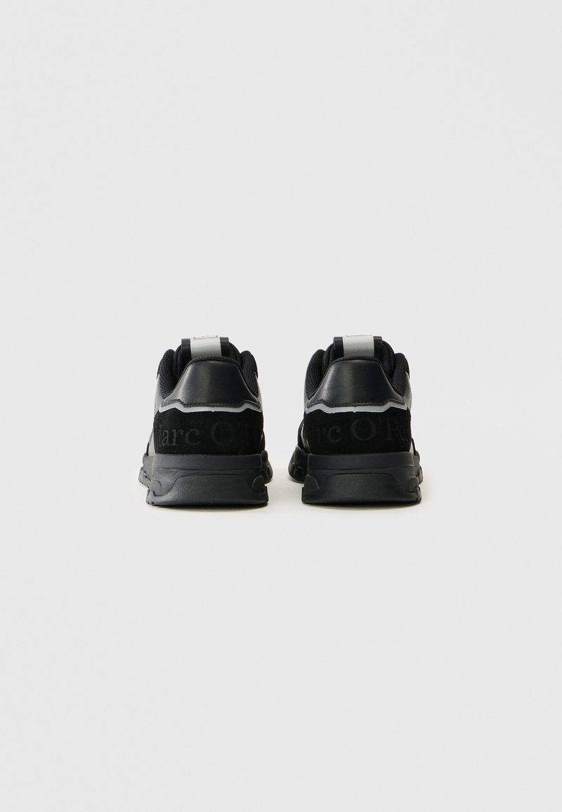 Schwarze sportliche Sneaker mit einem Obermaterial aus Wildleder und Synthetik, ausgestattet mit einer Zuglasche und einem geprägten Logo an der Ferse, texturiert und mit Gummisohlen.
