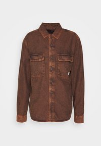 Brun denimskjorta med långa ärmar, knappstängning fram, två bröstfickor och subtil textur. Har kontrasterande sömmar och metallknappar.