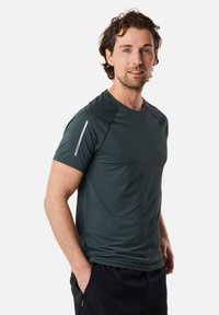 Donkergroen sport T-shirt van gladde, vochtafvoerende stof. Voorzien van korte mouwen en een reflecterende accent op de linker schouder.