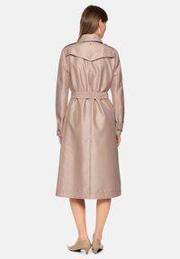 Langer Trenchcoat aus leichtem Taubengrau-Satin mit Gürtel. Verfügt über einen weiten Kragen, lange Ärmel und eine fließende Silhouette, die unterhalb des Knies endet.