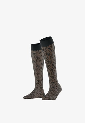 Chaussettes hautes transparentes avec motif de dentelle florale noire et bordure noire unie sur fond blanc uni.