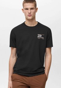 T-shirt in cotone nero con collo a giro; presenta una piccola grafica con testo e righe nella parte sinistra del petto.